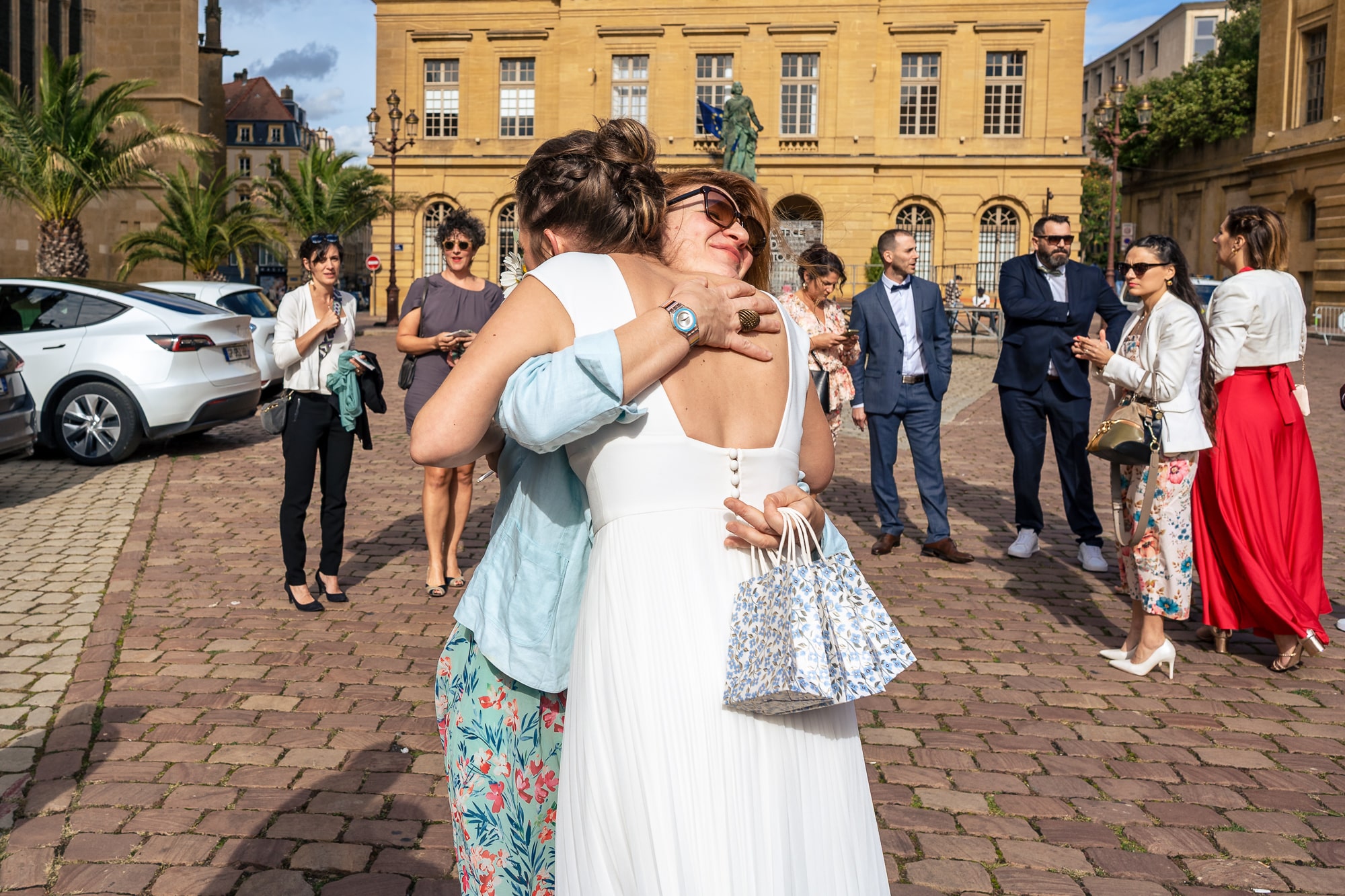 Une invitée serre la mariée dans ses bras à la sortie de la mairie